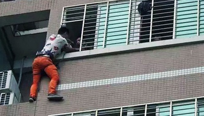 Vắt vẻo ngoài cửa sổ tầng 7 suốt đêm để tránh bị bắt gặp ngoại tình Các nhân viên cứu hộ đang cố gắng kéo người đàn ông trở ngược vào nhà.