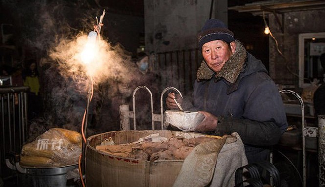 Cuộc sống mưu sinh trong giá rét kỷ lục ở Bắc Kinh Người đàn ông ngồi bán ngô trên đường phố trong giá rét kỷ lục ở Bắc Kinh.