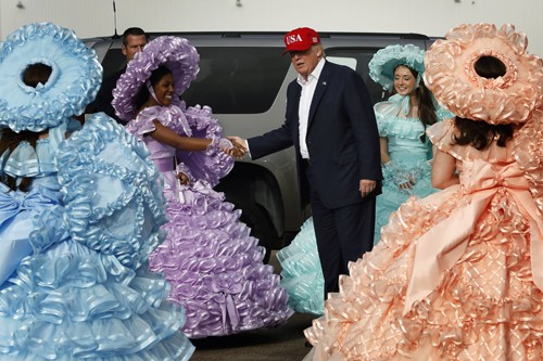 Dàn mỹ nữ mặc váy sặc sỡ chào đón ông Trump Các cô gái mặc váy chân phồng sặc sỡ chào đón ông Trump ở sân bay Mobile, Alabama hôm qua. Ảnh: Reuters.