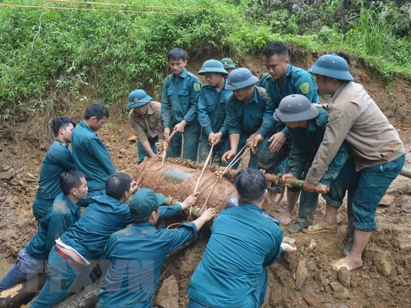 Bản tin 20H: Phá hủy quả bom Mỹ 350kg nằm gần đường sắt Hà Nội-Lào Cai Chiến sỹ lực lượng vũ trang đưa bom xuống hố để hủy nổ. Ảnh: TTXVN phát.