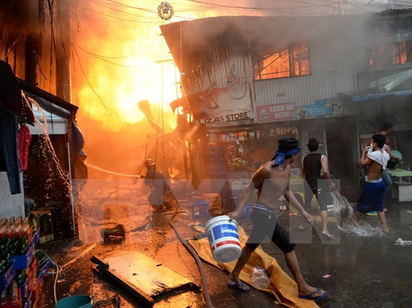 Bản tin 20H: Cháy khu Nhân viên cứu hỏa và người dân địa phương nỗ lực khống chế đám cháy dữ dội tại một khu dân cư nghèo ở khu vực ngoại ô thủ đô Manila. (Ảnh: AFP/TTXVN)