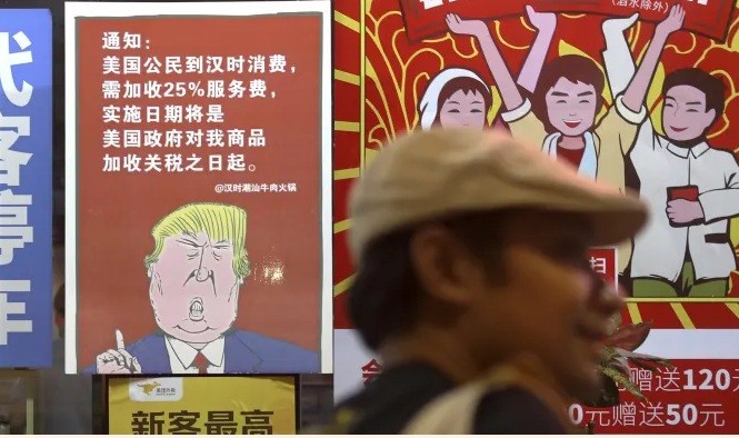 Dân mạng Trung Quốc chế giễu Mỹ trong cuộc chiến thương mại Một poster ở Quảng Châu có hình ông Trump kèm theo câu nói rằng tất cả khách hàng Mỹ sẽ bị đánh thuế 25% sau khi Mỹ tăng thuế lên hàng Trung Quốc. (Ảnh: AP)