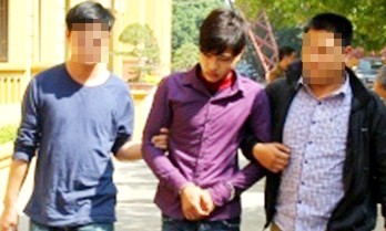 Học sinh lớp 12 giết dã man một phụ nữ lấy tiền tiêu Tết Phạm Minh Vương (giữa) đang được dẫn giải về trụ sở công an. Ảnh: Báo Công lý