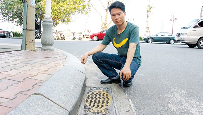 Chàng trai hiến hơn 100 'kế' cho thành phố Anh Lê Công Phúc bên cạnh nắp cống hình con cá với chất liệu composite dọc tuyến phố Bạch Đằng xuất phát từ ý tưởng của anh. Ảnh: Đào Phan.