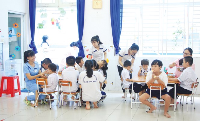 Những đứa trẻ tự kỷ không cô đơn Giáo viên đặc biệt cho trẻ ăn trưa. Ảnh: Ngô Tùng.