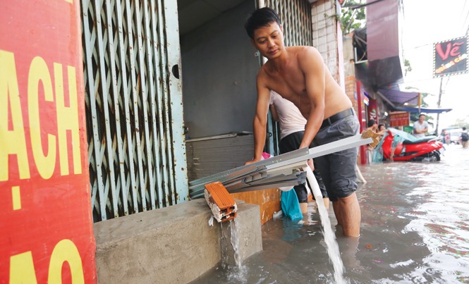 Chống cứ chống, ngập vẫn ngập Người dân bơm nước từ nhà ra mỗi khi trời mưa trên đường Phan Huy Ích (quận 12). Ảnh: Việt Văn.