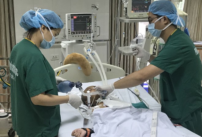 Chuyện nơi lằn ranh sống - chết: Những chiến binh thầm lặng Ðiều dưỡng Thảo và Giang đang hút dịch cho bệnh nhi hôn mê. Ảnh: Ảnh T.Hà.
