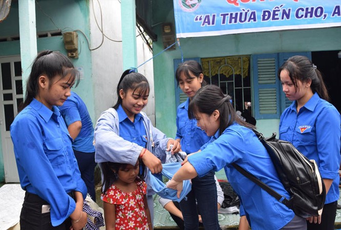 Quầy quần áo '0 đồng' tình thương mến thương Các bạn tình nguyện viên mặc đồ cho trẻ em. Ảnh: H.H.