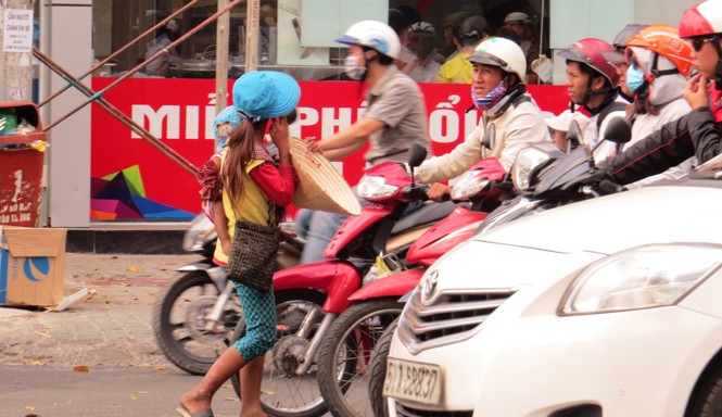 Vấn nạn ăn xin Bồng bế trẻ nhỏ chặn đầu ô tô xin tiền. Ảnh: Ngô Bình