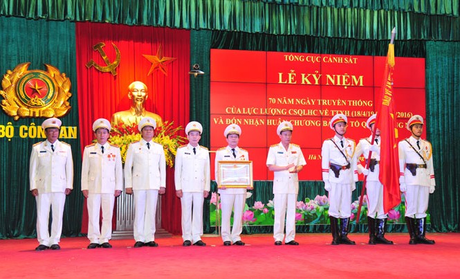 Đón nhận Huân chương Bảo vệ Tổ quốc hạng Nhất Lãnh đạo Bộ Công an tặng bằng khen và gắn huy chương lên cờ của lực lượng Cảnh sát QLHC và TTXH. Ảnh: Xuân Ân