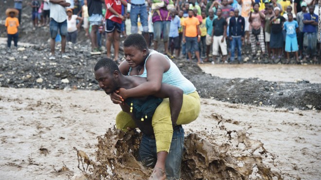 Haiti vật lộn với khó khăn sau bão lớn Người dân Haiti cõng nhau vượt sông vì cầu sập trong bão Matthew. Ảnh: Getty Images