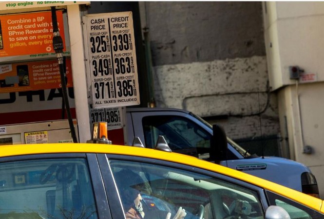  Một tài xế taxi đeo găng tay cao su vào đổ xăng trong khi giá xăng đã giảm do Covid-19 tại New York, Mỹ, ngày 14/3. Ảnh: Getty
