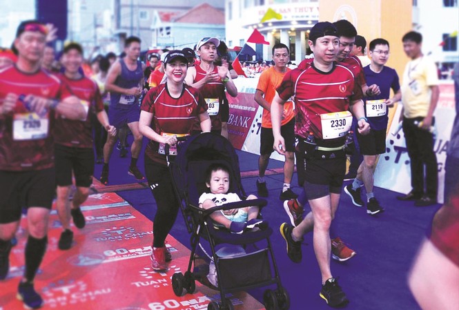 Cung đường hạnh phúc Tiền Phong marathon Gia đình chị Nguyễn Quỳnh Chi - Trần Phan Linh (38 tuổi) cùng con trai trên xe nôi xuất phát Ảnh: Xuân Tùng