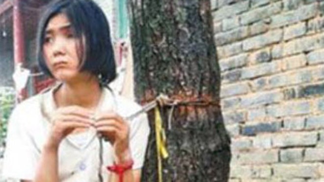 Bố mẹ trói con vào gốc cây 20 năm vì sợ đi lạc Zhang Yanrong bị trói vào cây. Ảnh: Shanghaiist