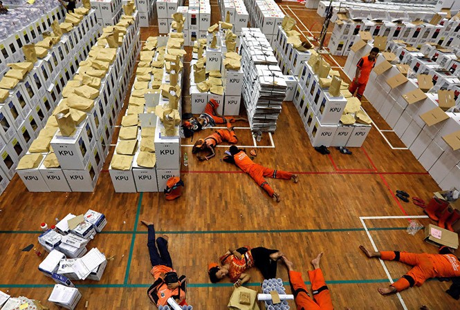 Hàng chục nhân viên kiểm phiếu chết vì kiệt sức trong cuộc bầu cử Indonesia Các nhân viên nằm nghỉ tại chỗ trong giờ giải lao trong khi chuẩn bị tài liệu bầu cử. Ảnh: Reuters