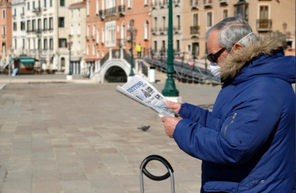 Italy: 368 ca tử vong trong 24 giờ, Thị trưởng Milan đích thân gom khẩu trang Một người dân đọc báo ở Venice (Ý) ngày 15/3. Ảnh: Reuters