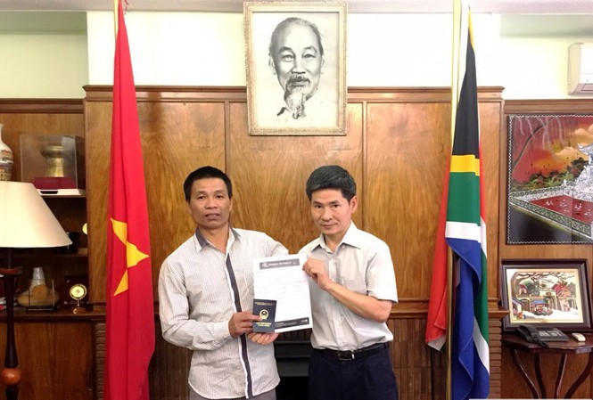 Hỗ trợ người Việt bị chủ tàu bỏ rơi ở Nam Phi Đại diện Đại sứ quán trao vé máy bay và giấy thông hành cho anh Nguyễn Văn Thanh. (nguồn: Đại sứ quán Việt Nam tại Nam Phi)