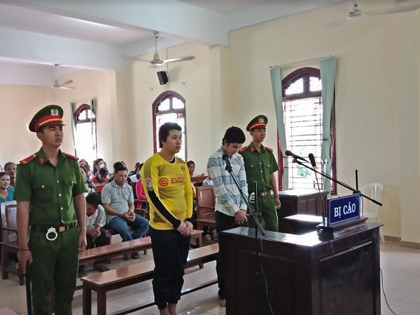 Thanh niên đồng tính đâm chết bạn nhậu lĩnh 20 năm tù Bị cáo Hiếu (áo vàng), Bình (áo sơ mi sọc) chờ nghe tuyên án. Ảnh: Kim Hà.