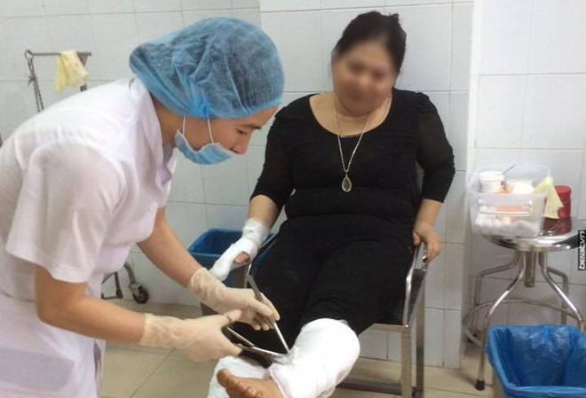Nữ giáo viên tưới xăng lên người và con rồi châm lửa đốt Chị Hương bị bỏng ở chân và tay đang được bác sĩ sơ cứu. Ảnh: Beat.vn