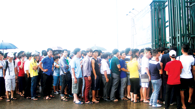 Người hâm mộ đội mưa xếp hàng mua vé chờ xem ĐT U19 VN trình diễn ở sân Mỹ Đình. ảnh: VSI