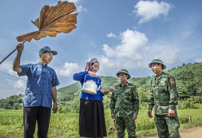 Vợ chồng bà Hoàng Thị Den rót bát nước chia tay bộ đội trên con đường làng. Ảnh: Lê Văn Chương.