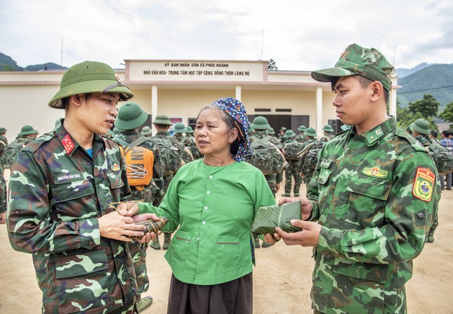 Bà Hoàng Thị En tặng bánh gai, bánh rơm cho bộ đội trong lễ chia tay. Ảnh: Lê Văn Chương.