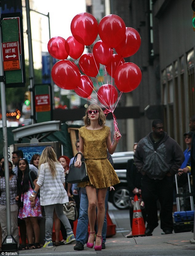 Taylor Swift walks down the street with a bunch of bright red balloons photo 1