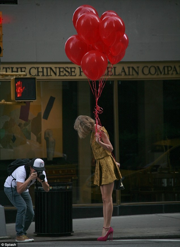 Taylor Swift walks down the street with a bunch of bright red balloons photo 2