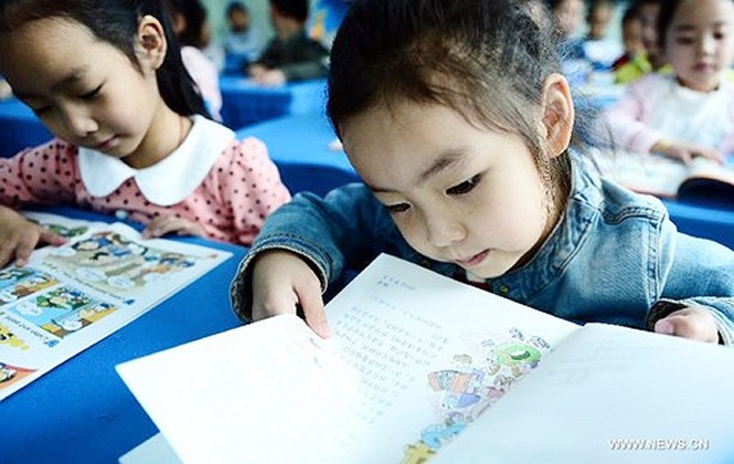 Tân học sinh Wen Yixin (phải) trường tiểu học Guchengtai, ở Xining, tỉnh Qinghai, Trung Quốc đang xem sách giáo khoa