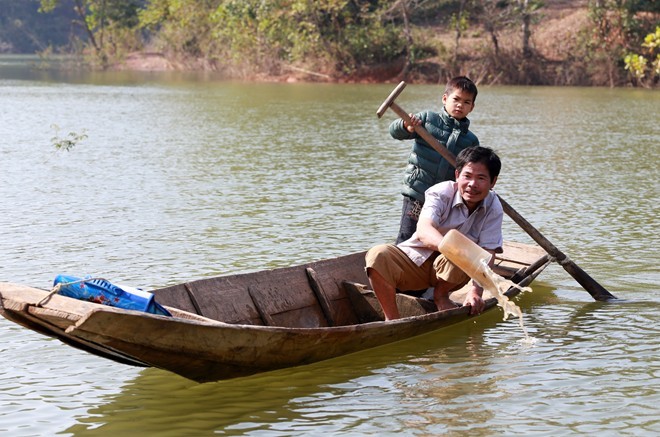 Em Đạt đi học về được bố đón, hai bố con thay nhau chèo, tát nước ra khỏi thuyền