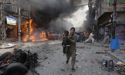 Người đàn ông Pakistan đang bế một bé gái chạy xa khỏi hiện trường một vụ đánh bom xe hơi tại thành phố Peshawar, phía Tây Bắc Pakistan