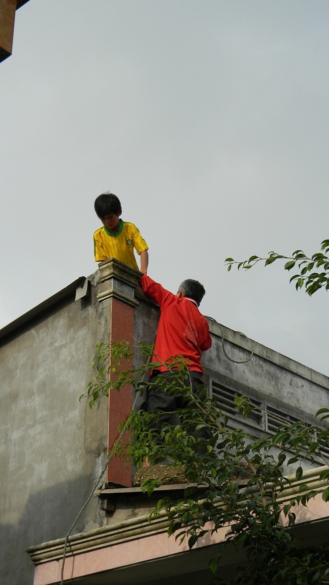 Tại vùng ven biển Tam Tiến, huyện Núi Thành, rất nhiều trẻ em, người già trèo lên mái nhà kéo bao cát chằng mái tôn