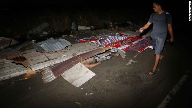 Thi thể một người đàn ông Philippines bị mắc kẹt dưới đống đổ nát sau khi cơn bão Haiyan quét qua. Nhiều người Philippines cũng đang đi tìm thi thể người nhà của mình