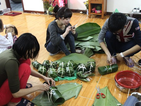 Trung (bên phải) và các bạn gói thêm lớp lá dong phía ngoài cây giò cho đẹp mắt