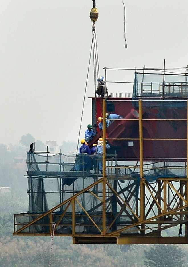 Các công nhân làm việc trên mép nối giữa hai trụ tháp khổng lồ