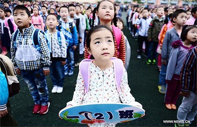 Bé Yang Xinyue (giữa) – tân học sinh của trường tiểu học Guchengtai, ở Xining, tỉnh Qinghai, Trung Quốc dự lễ chào cờ đầu tiên trong năm học mới trong ngày khai giảng năm học mới ngày 1/9