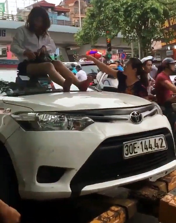 Nữ tài xế taxi mặc váy ngồi nóc ô tô chống đối CSGT - ảnh 1