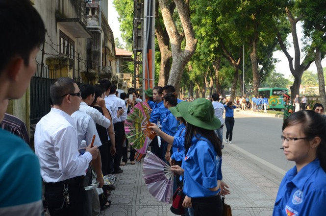 Những sinh viên tình nguyện quạt cho người dân đang xếp hàng