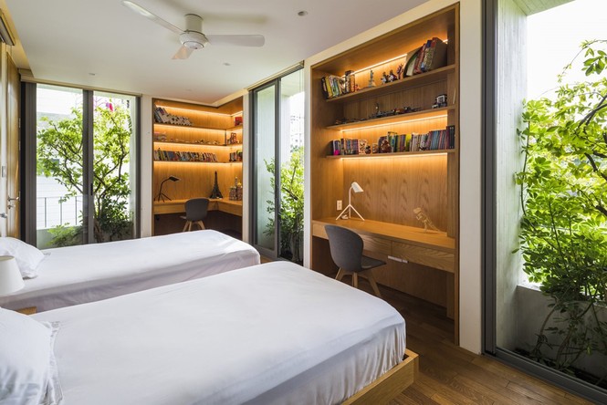 Phòng ngủ được thiết kế tinh tế với hai khu vực bàn học riêng biệt nhưng vẫn có sự gắn kết với cây cối.