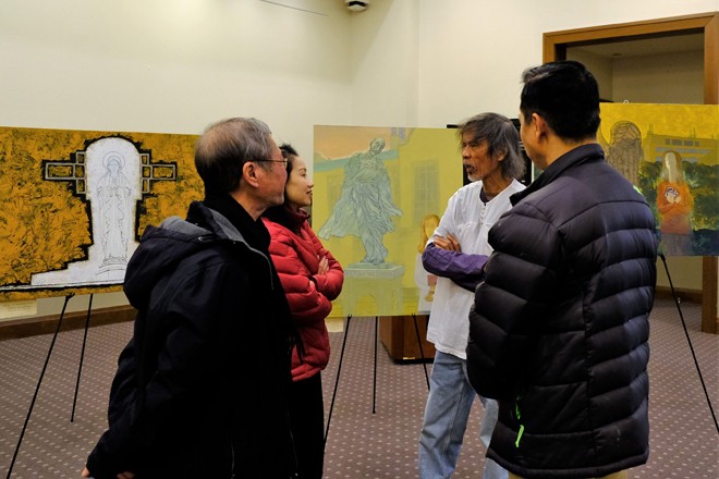 Họa sĩ Phan Ngọc Minh - áo trắng - trao đổi với người xem tại triển lãm của ông tại Boston College