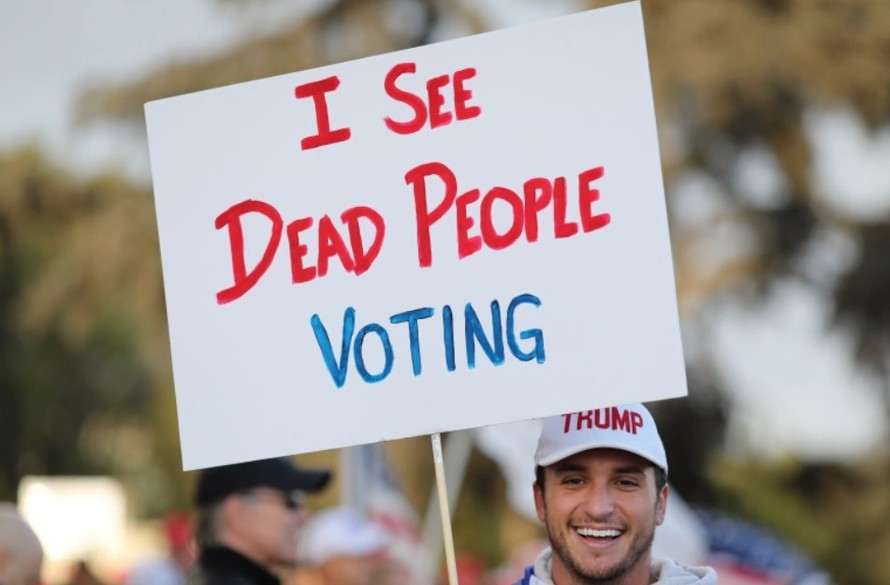 Cử tri ủng hộ ông Trump cầm biểu ngữ "Tôi thấy người chết đi bỏ phiếu". Ảnh: AP
