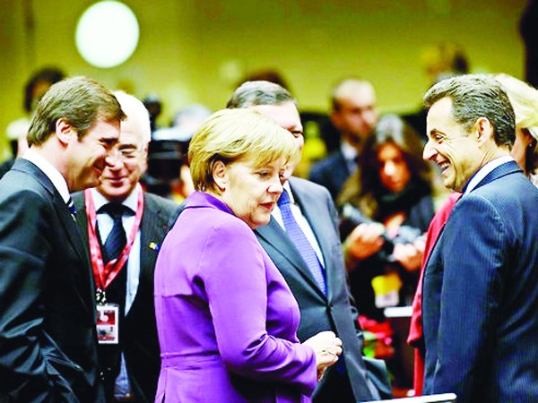 Thủ tướng Đức Angela Merkel (giữa) và Tổng thống Pháp Nicolas Sarkozy (bìa phải) vui vẻ trao đổi bên lề Hội nghị Thượng đỉnh EU hôm 9-12. Ảnh: Bloomberg