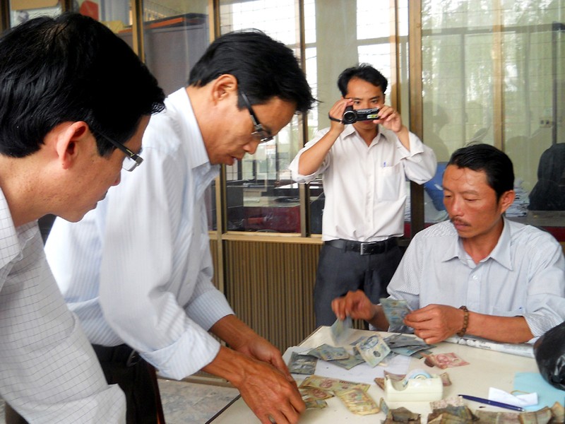 Cán bộ Ngân hàng Nhà nước kiểm tra số tiền bị cháy của tiểu thương Lương Hồng Thắng