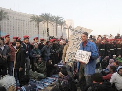 Sáng 13-2, binh sĩ Ai Cập đứng quanh những người biểu tình còn ở lại Quảng trường Tahrir tại thủ đô Cairo, giúp họ trở lại cuộc sống bình thường Ảnh: AP