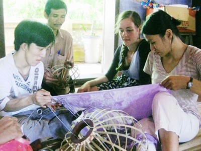 Nguyễn Thị Thuý Phương (phải) đang cùng tình nguyện viên nước ngoài hướng dẫn cách làm đèn lồng cho thanh niên khuyết tật