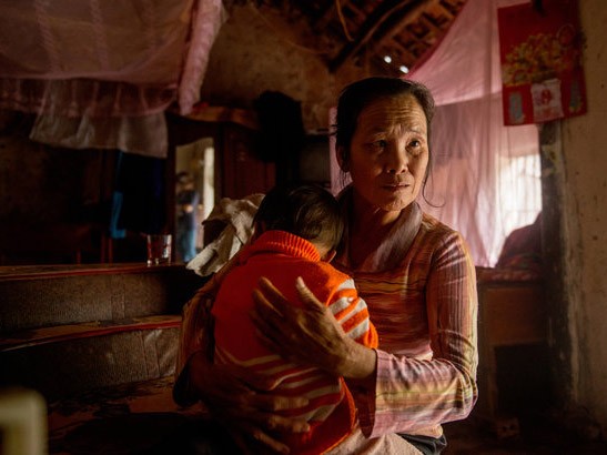 Bà Nguyễn Thị Nhan cùng cháu nhỏ trong ngôi nhà ở làng không chồng, làng Lòi, Nghệ An