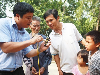 Đặng Minh Chưởng (bìa trái) đang hướng dẫn cách sử dụng điện an toàn tiết kiệm cho bà con nông dân xóm 1 xã Nam Cường. Ảnh: Phùng Nguyên