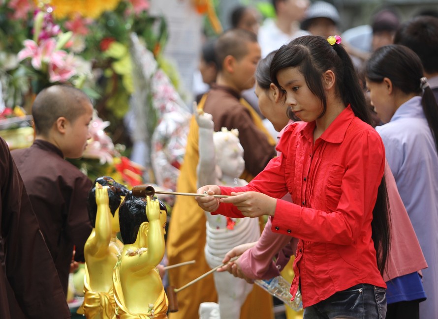 Nhiều bạn trẻ thành kính bưng gáo nước thơm bằng cả 2 tay tắm cho Phật