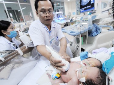 Bác sĩ Nguyễn Hữu Chí, trưởng khoa siêu âm Bệnh viện Nhi Đồng 1 (TP.HCM), siêu âm tổng quát cho bé gái hai đầu tại khoa hồi sức sơ sinh. Ảnh: Minh Đức