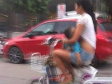 Người mẹ trẻ vừa đi xe đạp vừa cho con bú trên đường phố Trung Quốc
